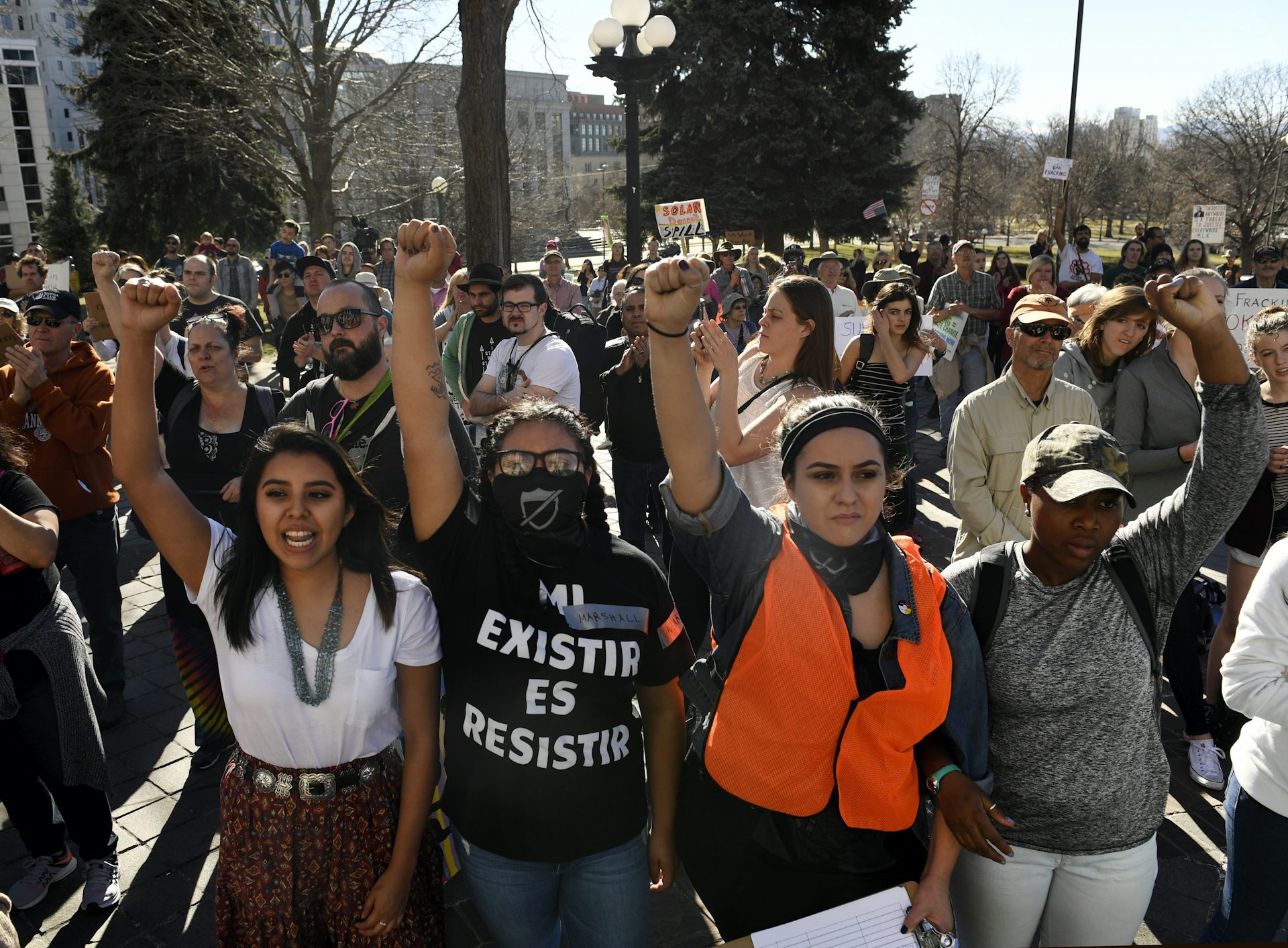 A group of young people march together, holding their fists in the air.