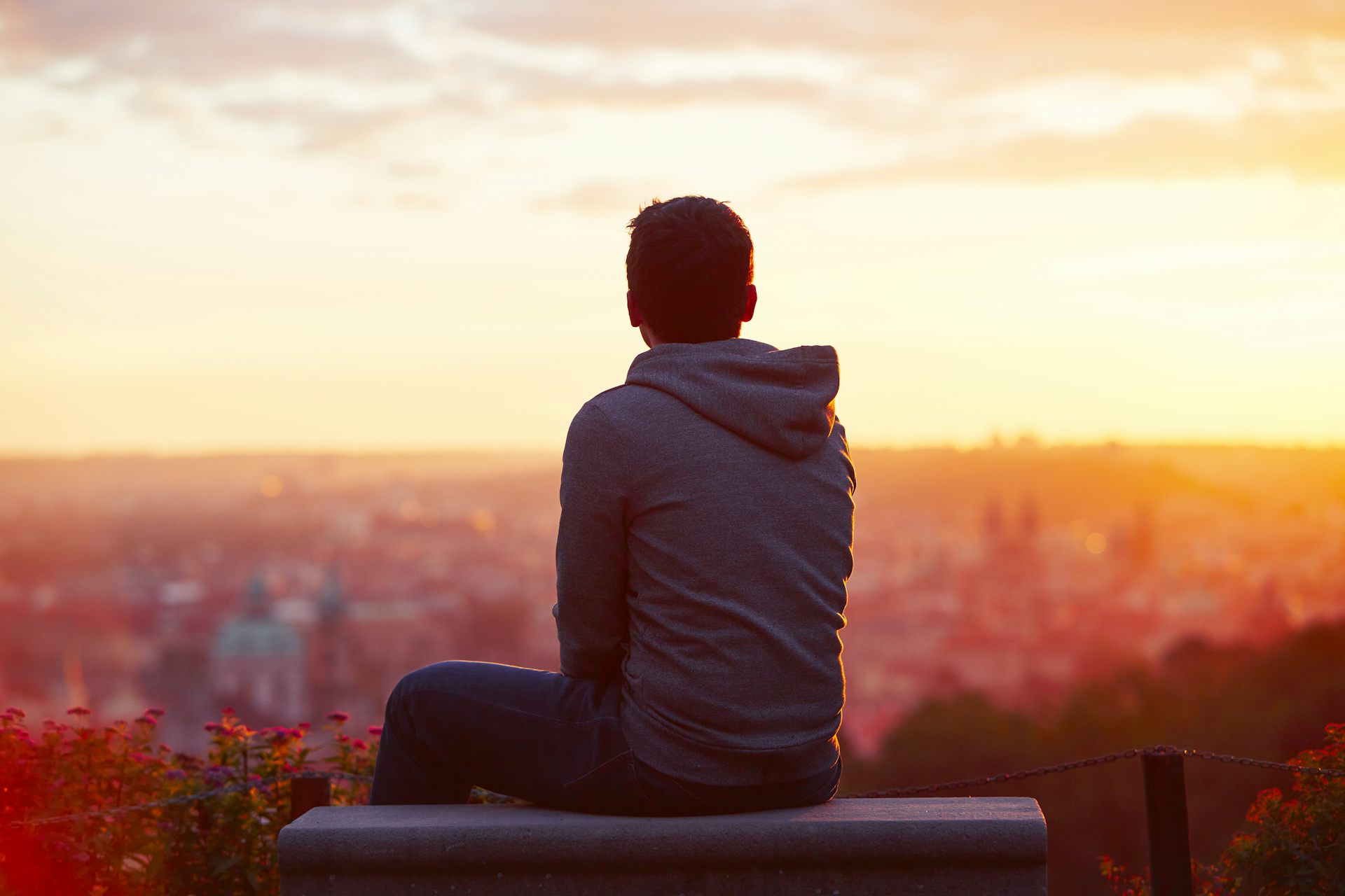 A man sits alone looking over a cityscape A man sits alone looking over a cityscape
